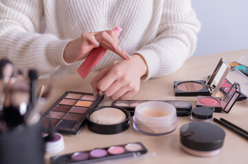 A faceless woman watches online training from a professional makeup artist on a laptop. Distance learning