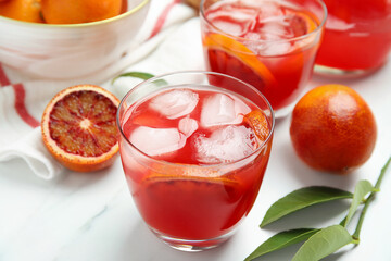 Tasty sicilian orange juice with ice cubes and fruits on white marble table