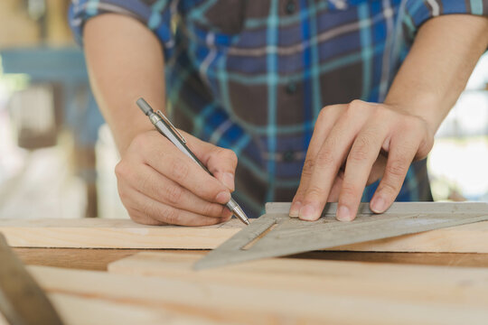 Carpentry professional, hand of asian young man, male carpenter use ruler measure, tool on board wood in small shop. Woodwork, furniture making, construction industry. Owner small business people.