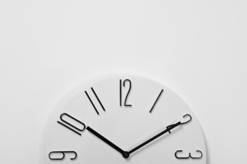 Stylish analog clock hanging on white wall, space for text
