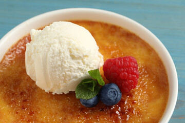 Delicious creme brulee with scoop of ice cream, fresh berries and mint on light blue background, closeup