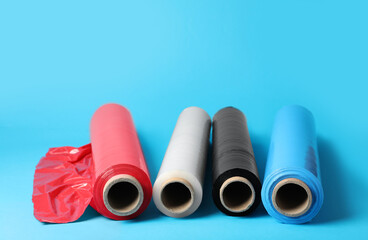 Rolls of different plastic stretch wrap on light blue background. Space for text