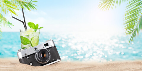 Retro camera and mojito cocktail on tropical beach