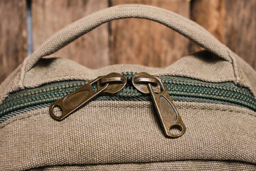 Closed zipper with two sliders on a brown hiking backpack.