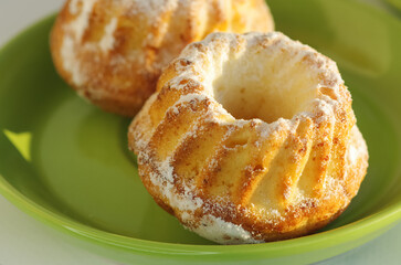 Delicious muffins sprinkled with powdered sugar on a green plate.