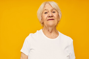 Portrait of an old friendly woman posing face grimace joy yellow background