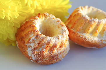 Fresh appetizing muffins on a background of yellow chrysanthemums. Sweets.