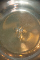 cross printed in a stainless steel vessel at a baptism,Orthodox Church, Romania 
