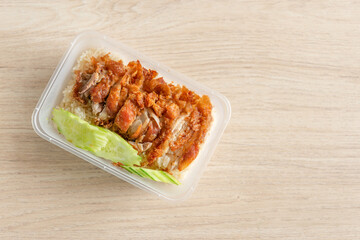 steamed rice topped with chicken in a plastic box on the table.