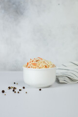 Sauerkraut in a white cup on a light background.