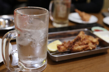 泡盛のジョッキと料理が並ぶ飲み会のテーブル