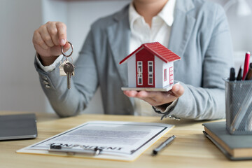 Insurance concept the real estate representative holding a house key on the right hand and the house model on the left hand