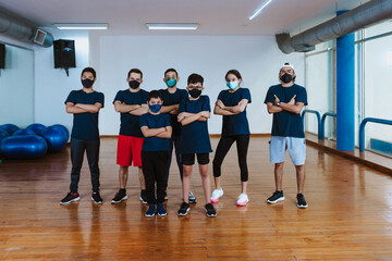 Fototapeta na wymiar Latin teenagers and hispanic children with trainer instructor man with face mask for coronavirus covid pandemic in work out sport class in Mexico Latin America