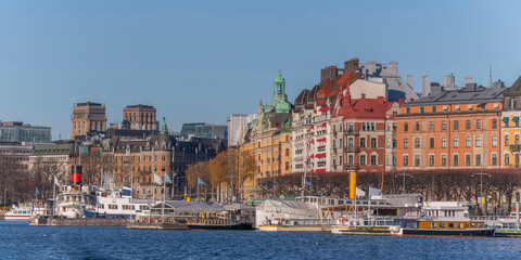 Fototapeta na wymiar Panorama view over a creek of the bay Ladugårdsviken with commuting boats surrounded by office and hotel buildings a sunny winter day in Stockholm