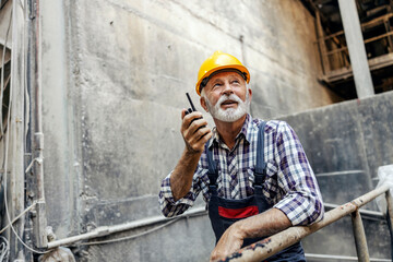 An old factory worker with communicates with coworkers over the walkie-talkie.