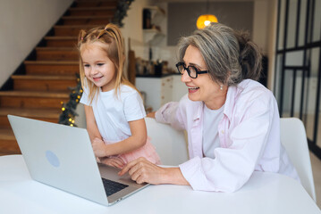 Child and granny looking at the camera with laptop