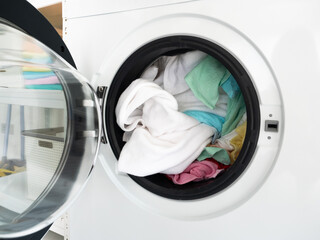 Open front load washing machine and put color clothes before press automatic button for cleaning them in laundry service