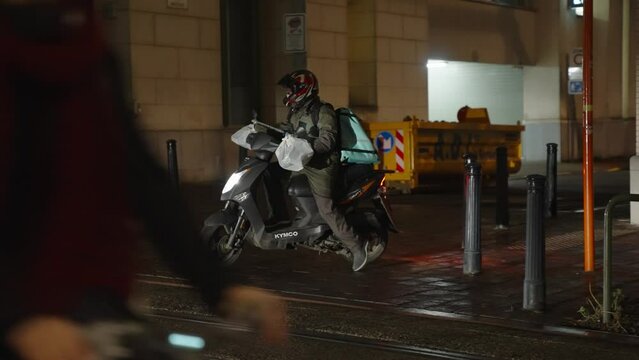 Deliveroo food rider on a scooter in the evening. Concept of takeaway, home delivery, new eating habits, public transport