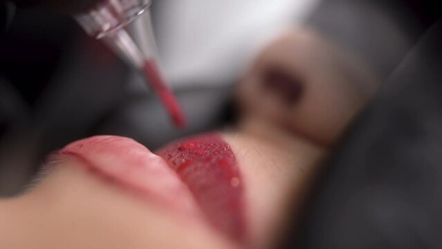 process woman applying permanent tattoo makeup on lips in beautician salon, lip microblading pigment