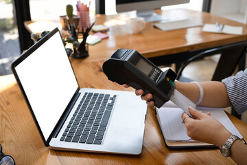 Young woman swiping a credit card in card reader machine.