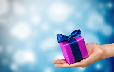 Hands holds Christmas gift on snow bokeh background