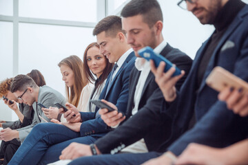 Obraz premium group of young business people looking at their smartphone screens.