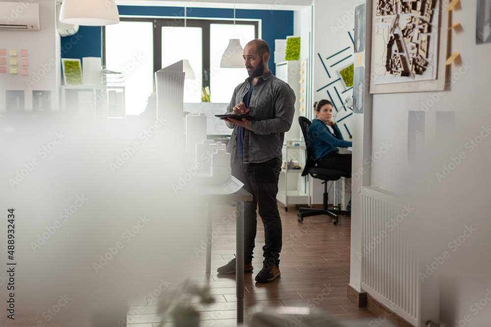 Poster wide view of architectural engineer holding tablet looking in the distance thinking about improving 
