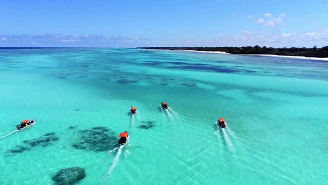 Group of small african motorboats on the tropical Indian Ocean. Zanzibar with young people diving. Drone 4k follow dolly shot