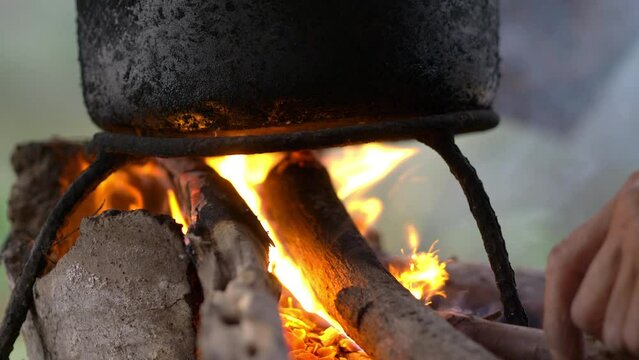 Close up, Hands of Senior man with firewood to burn in stove to steamed sticky rice with, The simble life of the rural people in Thailand