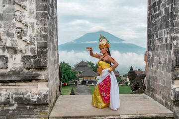 Young traditional Bali dancer wearing a traditional costume in mountain temple.