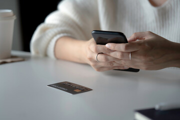 Female hands using smartphone with credit card on the table. Online shopping