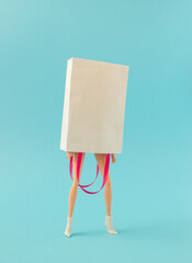 Girl wearnig white paper bag over head and high heels on blue background. Minima fashion or ...