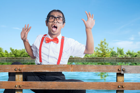Asian nerd with ugly face falling from wooden fence