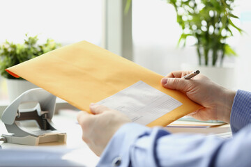Man holding yellow envelope and going to fill in personal address on cover