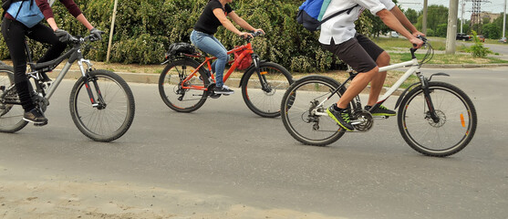 Three cyclists without faces on an asphalt road, motion blur. City bike ride, people in casual...