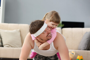 Father and daughter have fun playing together, physical exercise with kid on back