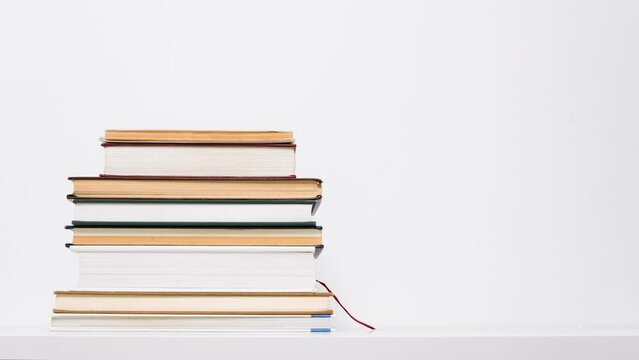 Stop motion animation of growing and shrinking stack of books isolated on white background. Educational or learning concept.