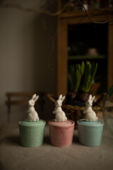 candles in ceramic containers top view. ceramic candlestick with a lid in the shape of a rabbit. decorative candles on the table near potted plants. ceramic figurine of a bunny