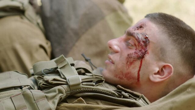 Severely injured soldier is resting with his teammate as they talk to each other and come up with a plan in this hopeless situation. Close up shot