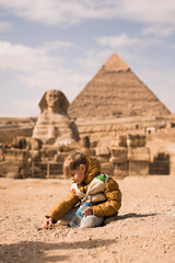 boy plaing on background of Great Sphinx and Chephren's pyramid in Giza, Egypt