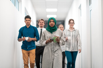 Multi-ethnic startup business team walking through the hallway of the building while coming back from a coffee break