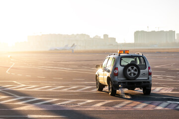 Scenic view of airport security car on tarmac apron taxiway in warm sunlight of bright morning...