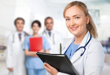 Portrait of happy young nurse in uniform with healthcare team in background. Successful doctor and nurses