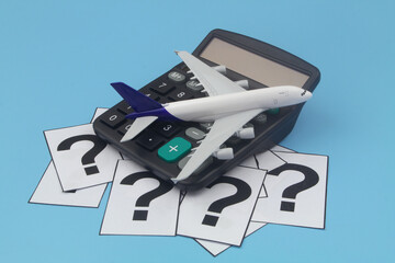 Airplane tickets price and travel budget concept. Airplane model and calculator on question marks...