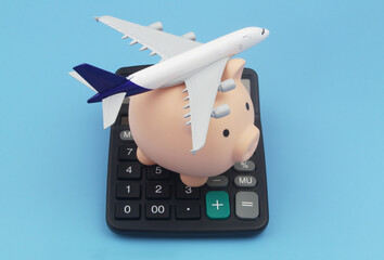 Save money and travel budget and tickets price concept. Airplane and piggy bank on calculator.