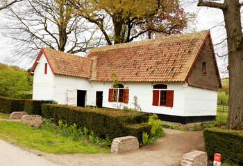 Fototapeta na wymiar White farmhouse with red windows in a rural landscape, Bokrijk, Belgium