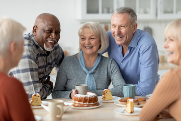 Cheerful senior people drinking tea with cake together