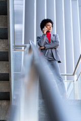 Elegante mujer afroamericana utilizando el teléfono móvil en un edificio de oficinas 