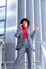 Elegante mujer afroamericana utilizando el teléfono móvil en un edificio de oficinas 