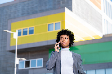 Elegante mujer afroamericana utilizando el teléfono móvil en un edificio de oficinas 